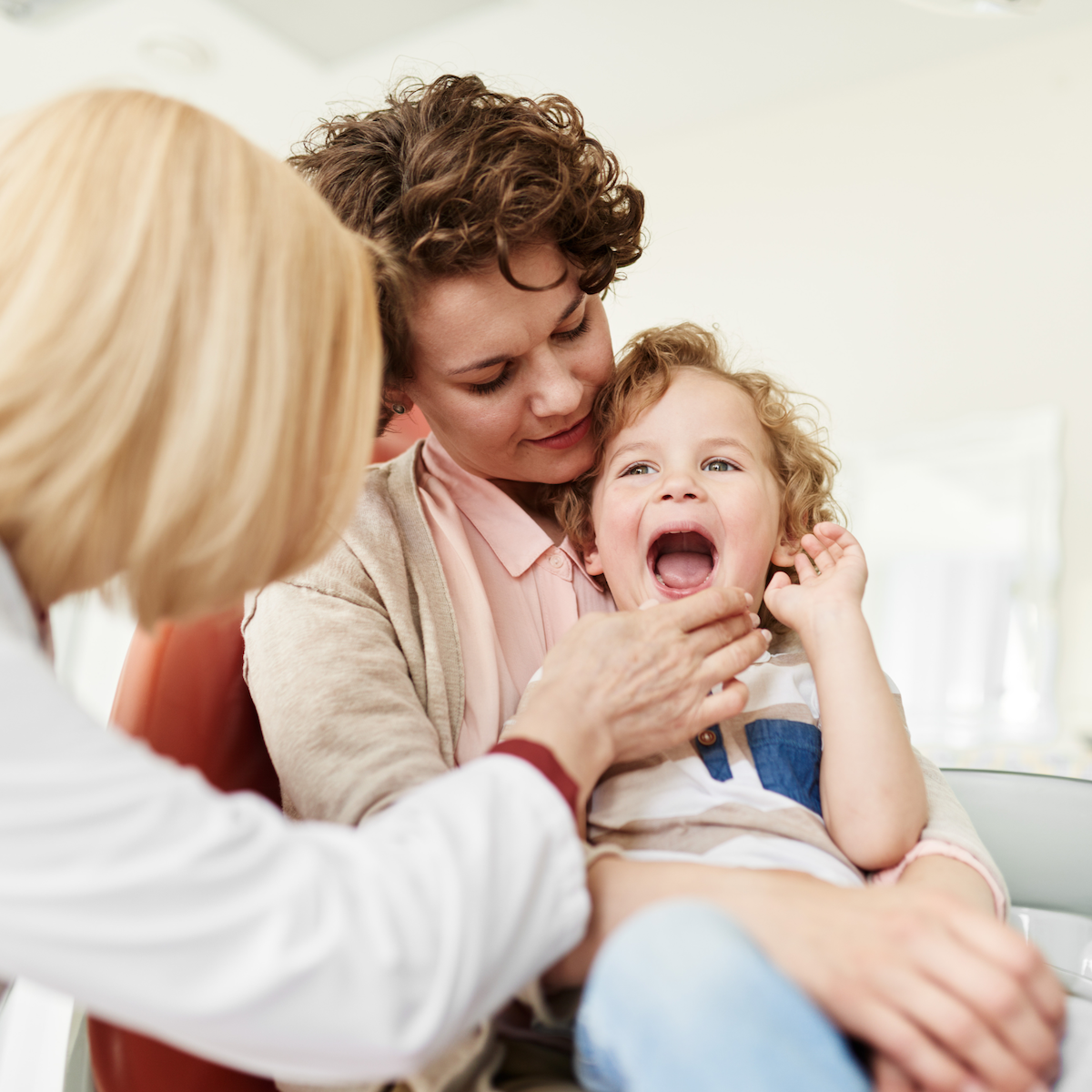 Mom holding toddler during a doctor visit.