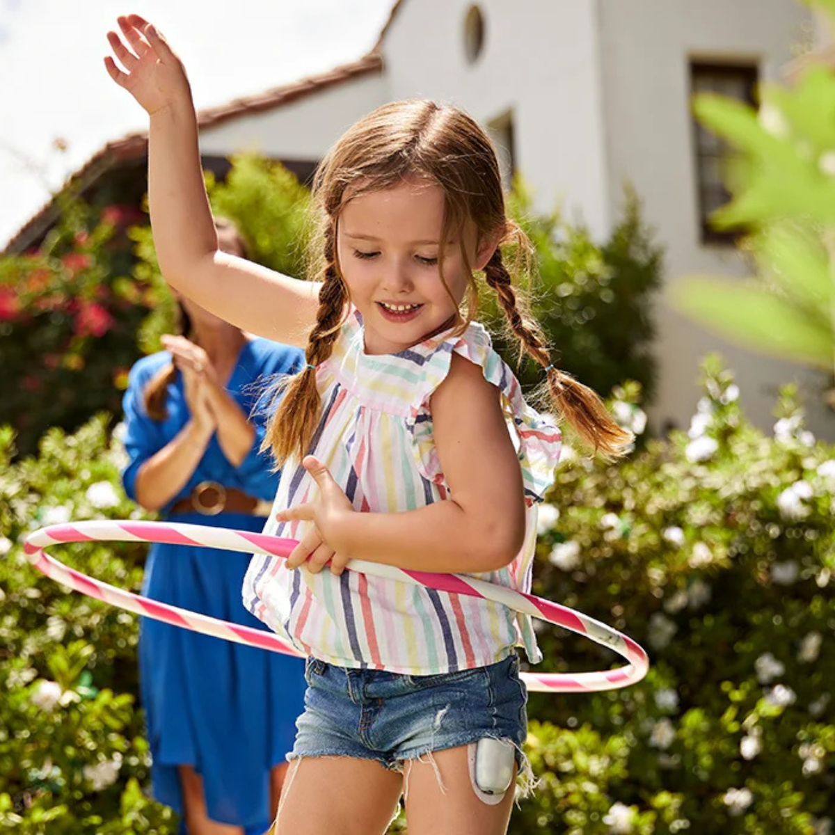 Young girl hula-hooping with an Omnipod device on her leg.