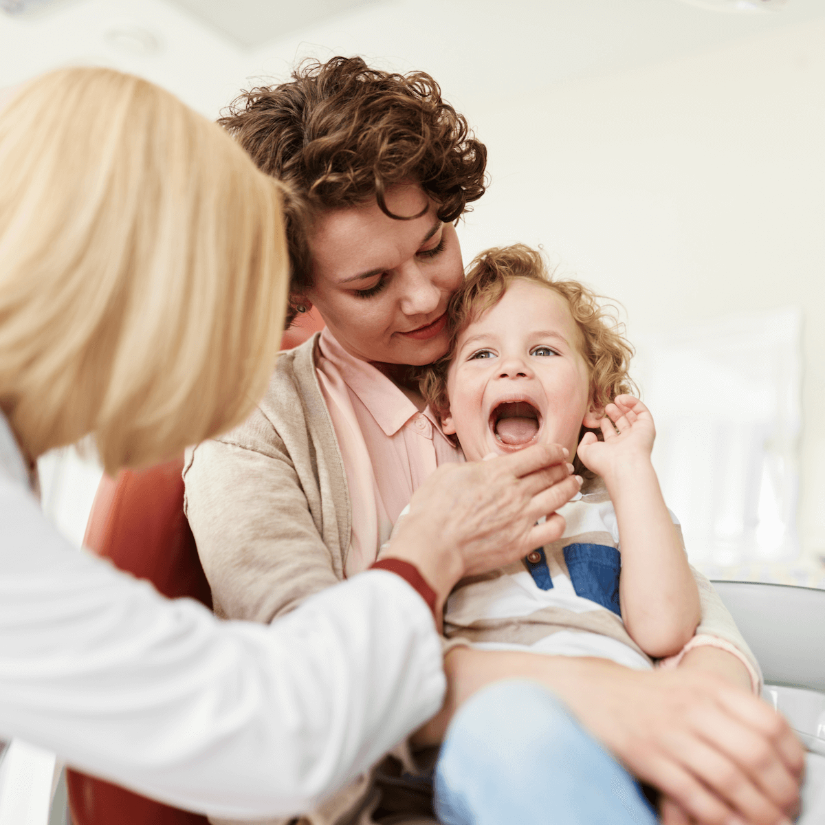 Mom holds daughter while doctor speaks with them.