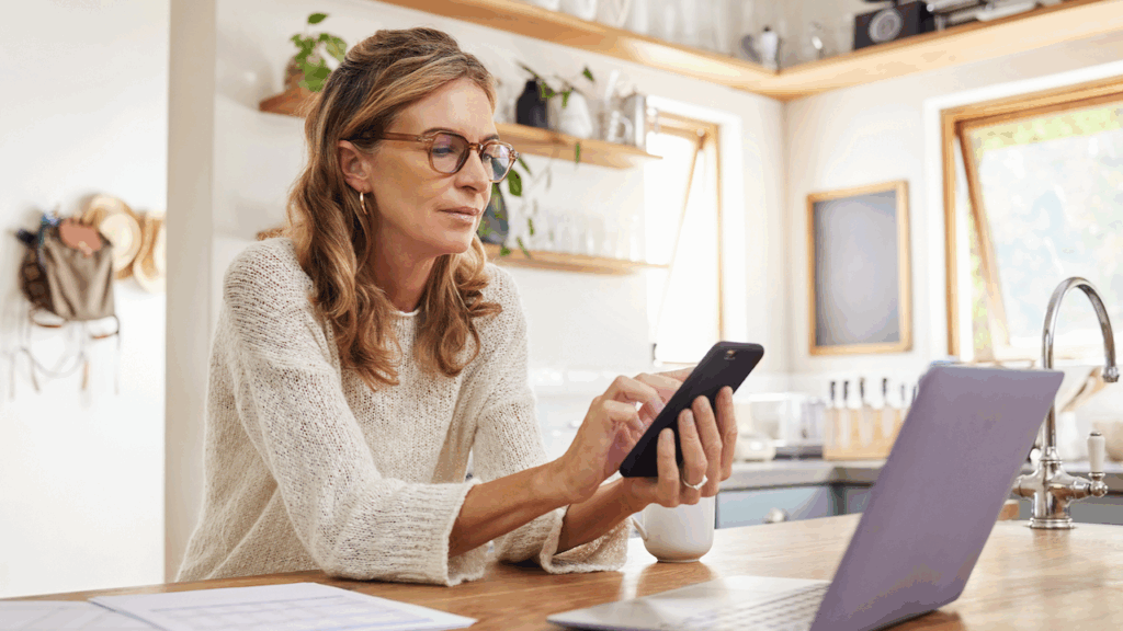 Women using phone and laptop while at home.